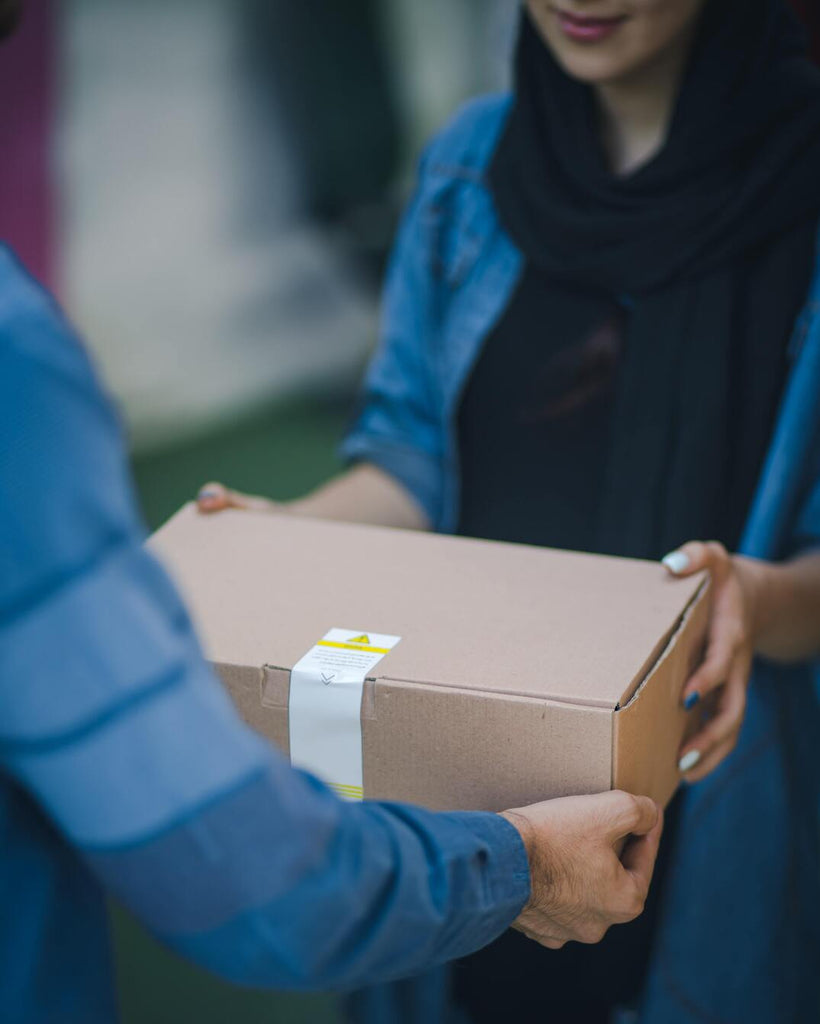 A woman in a hijab receiving a package delivery.